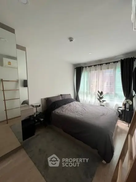 Modern bedroom with large window and stylish decor in a cozy apartment.