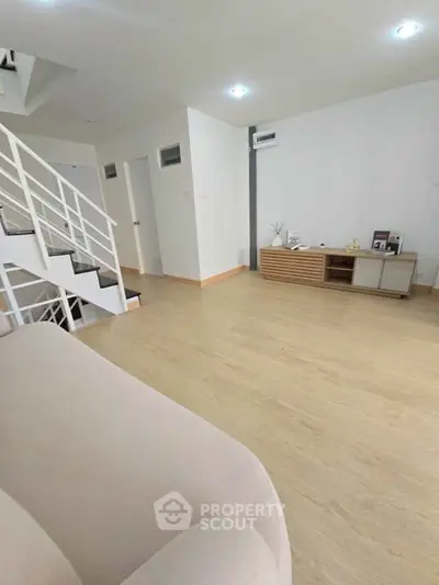 Spacious modern living room with wooden flooring and stylish staircase