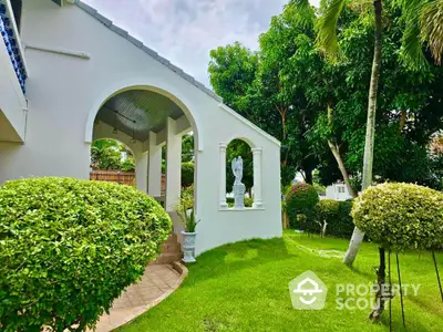 Charming garden view with elegant archway and lush greenery in a serene residential setting.