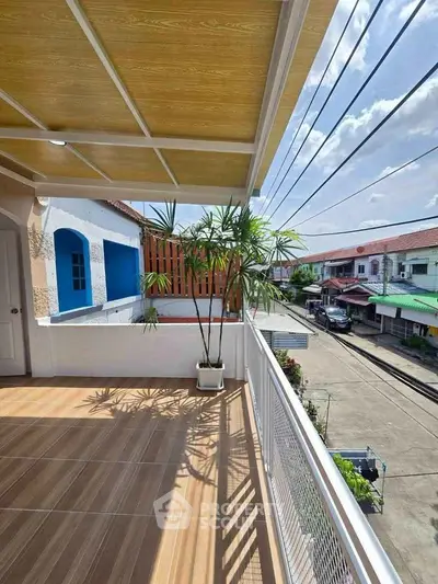 Spacious balcony with street view and potted plant, perfect for relaxation.