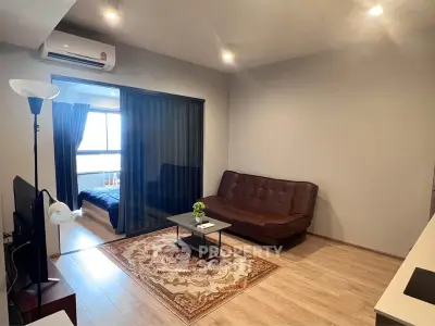 Modern living room with wooden flooring, cozy sofa, and adjacent bedroom view.