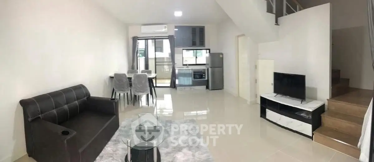 Modern open-plan living room with sleek furniture and compact kitchen area, ideal for urban living.