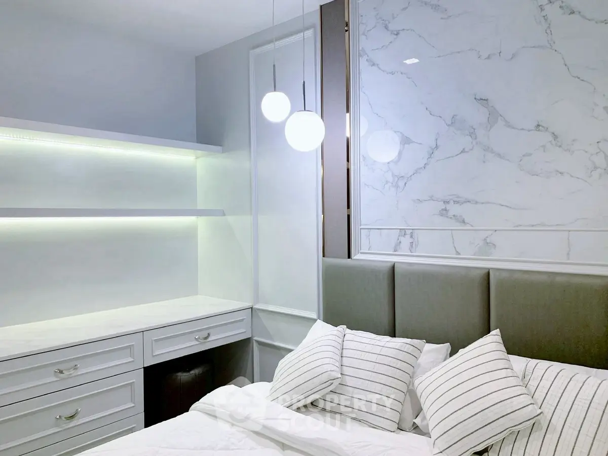 Modern bedroom with elegant marble accent wall and sleek lighting.