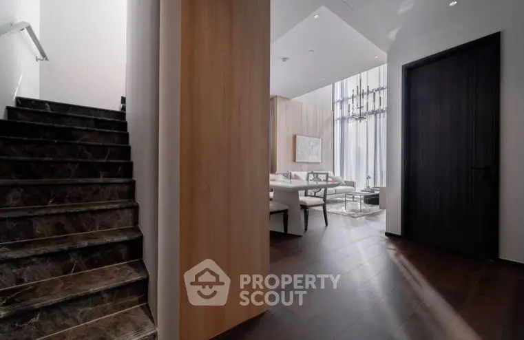 Luxurious modern interior with elegant staircase and spacious living area, featuring high ceilings and stylish decor.