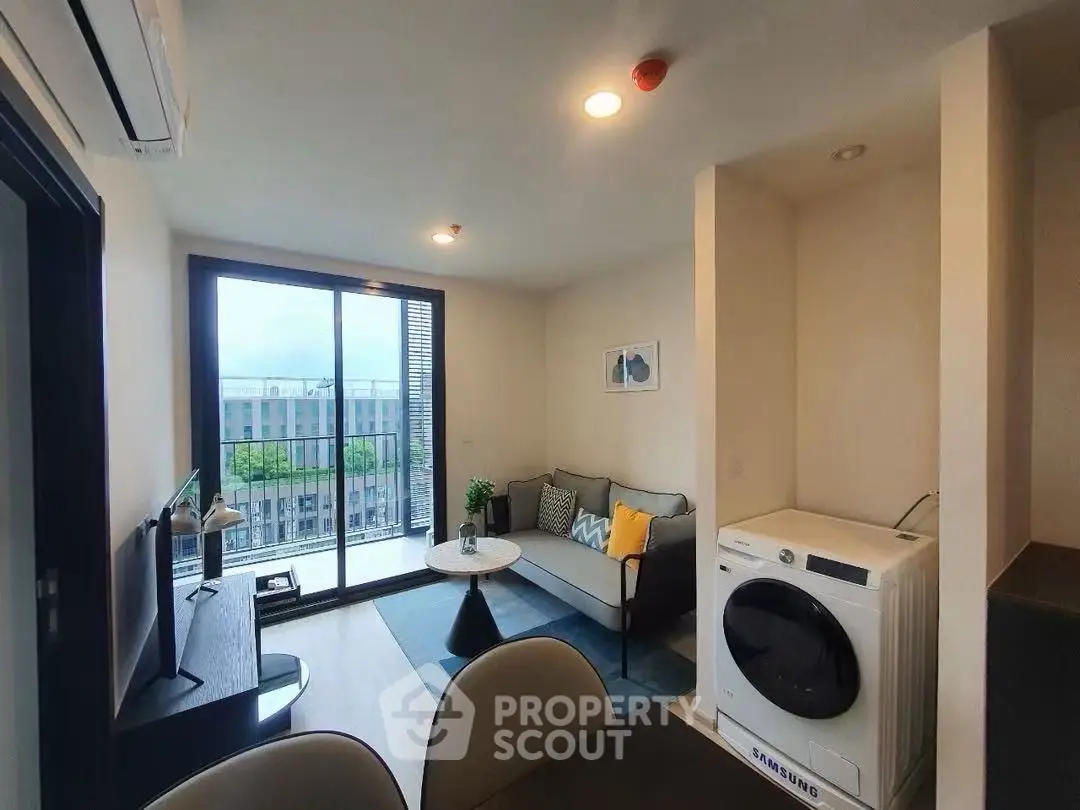 Modern living room with balcony and washing machine, featuring stylish decor and natural light.