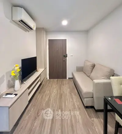 Modern living room with sleek design and cozy sofa, featuring a flat-screen TV and air conditioning.