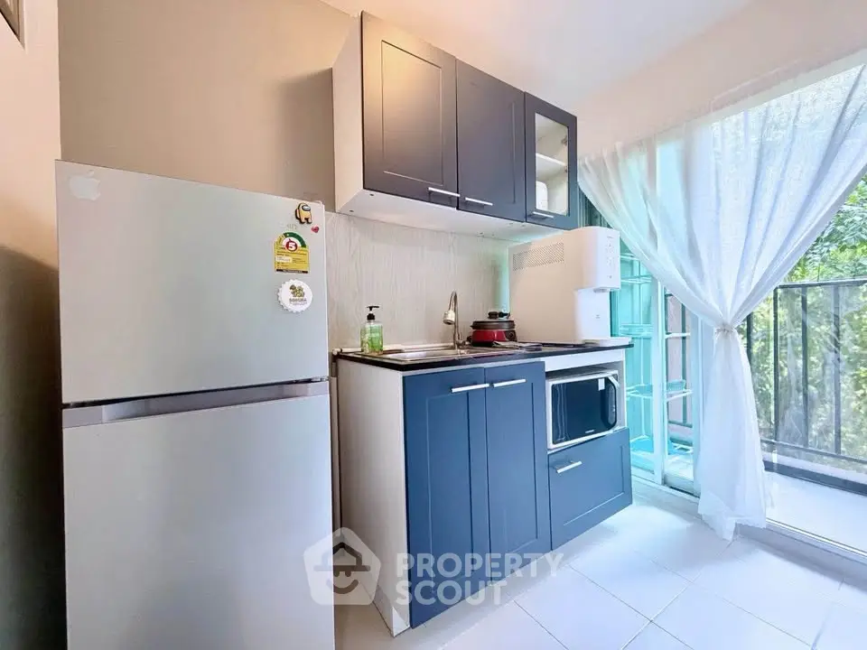 Charming kitchen with modern appliances and balcony view, perfect for cozy urban living.