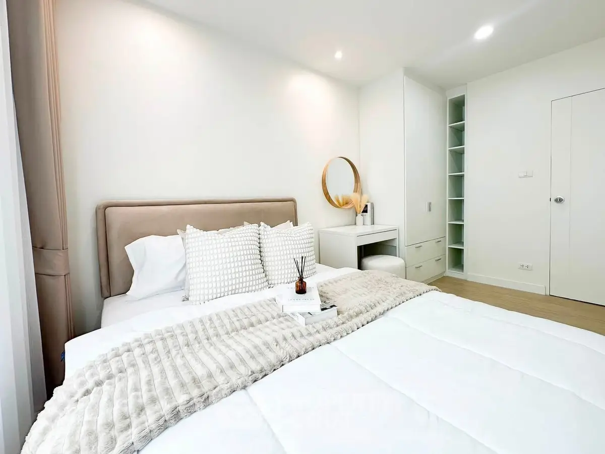 Elegant bedroom with cozy bedding and modern decor in a bright, minimalist design.