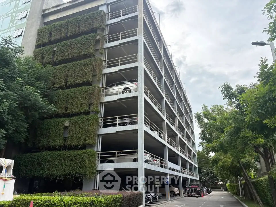 Modern multi-level parking structure with green facade and ample parking space.
