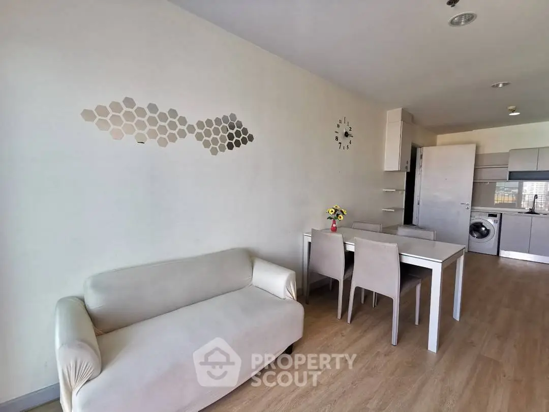 Modern open-plan living room with dining area and kitchen, featuring sleek furniture and wall decor.