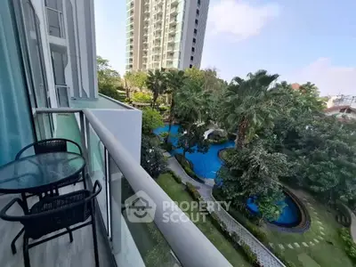 Stunning balcony view overlooking lush garden and pool in modern high-rise apartment.