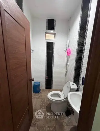 Compact bathroom with modern fixtures and tiled walls, featuring a toilet and bidet.