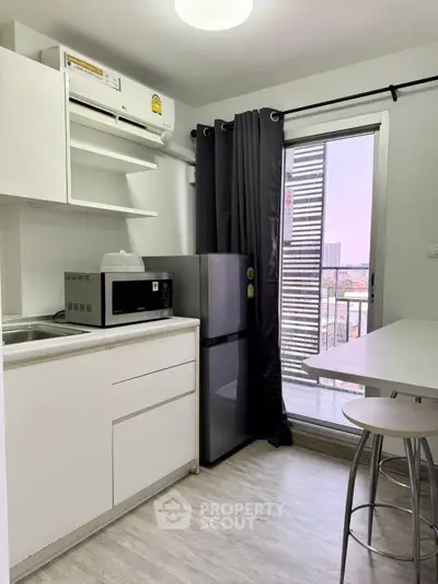 Modern kitchen with sleek appliances and balcony view in urban apartment