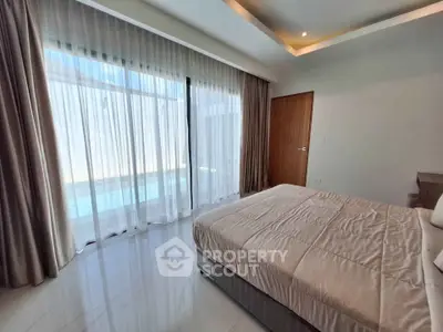 Luxurious bedroom with floor-to-ceiling windows and pool view, featuring elegant curtains and modern decor.