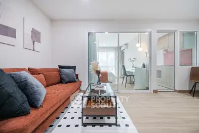 Modern living room with stylish decor and glass partition leading to a bright study area.