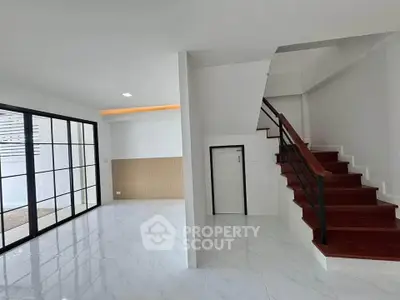 Modern interior with sleek staircase and spacious living area featuring large windows.