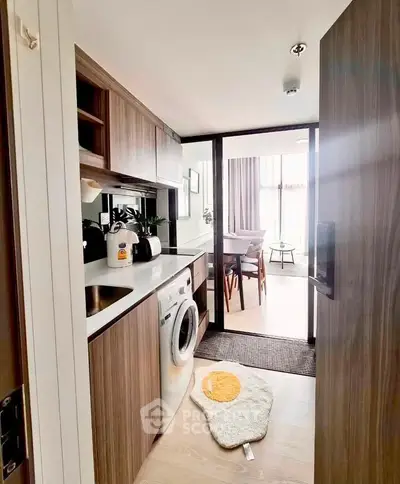 Modern kitchen with washing machine and open layout leading to dining area