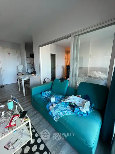 Cozy living room with teal sofa and modern decor in a compact apartment.