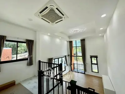 Spacious modern living room with high ceilings and large windows offering natural light and garden views.