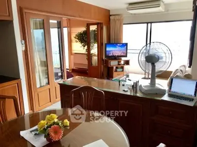 Spacious living room with large windows and wooden furniture, featuring a cozy seating area and modern amenities.