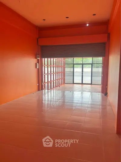 Spacious commercial space with vibrant orange walls and large front windows, ideal for retail or office use.