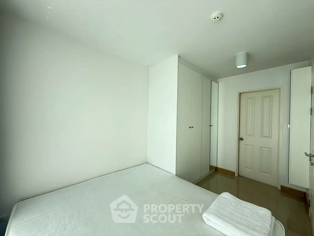 Spacious minimalist bedroom with white walls and built-in wardrobe, perfect for modern living.