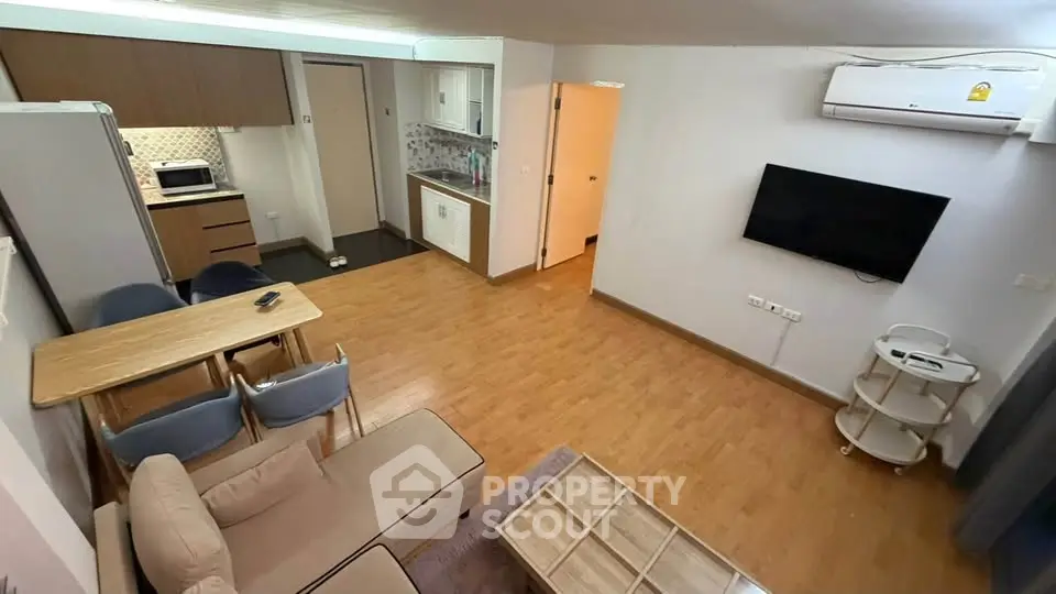 Modern open-plan living room with kitchen, featuring wooden flooring and contemporary furniture.