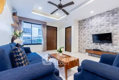 Modern living room with blue sofas, wooden coffee table, and wall-mounted TV.