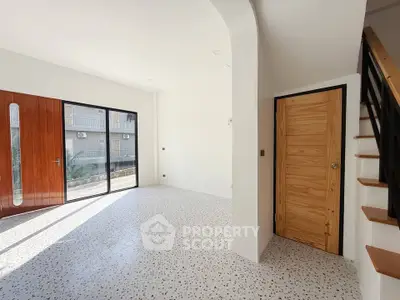 Spacious modern living room with terrazzo flooring and wooden accents, featuring large windows for natural light.