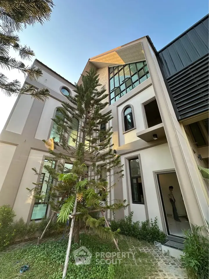 Modern architectural home exterior with large windows and lush greenery