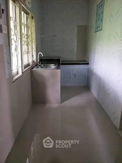 Compact kitchen with tiled walls and a single sink, featuring a closed cabinet layout.