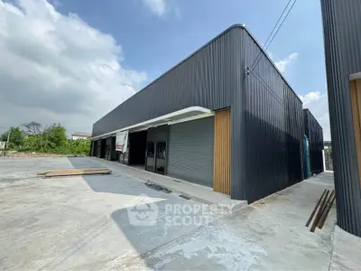 Modern industrial warehouse with sleek black exterior and spacious concrete yard.