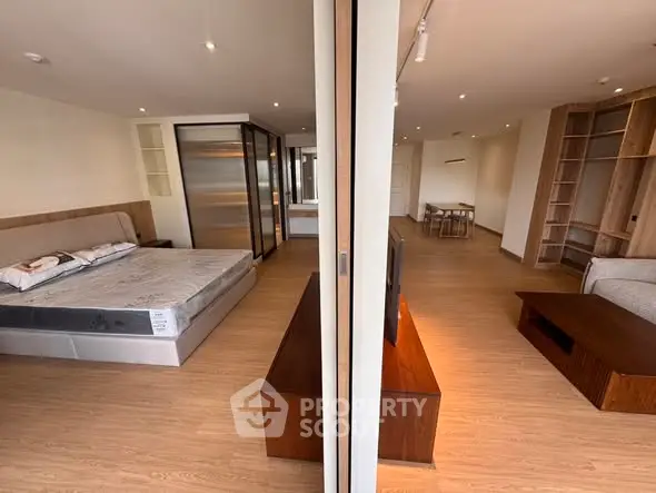 Spacious modern apartment with open layout, featuring a cozy living area and elegant bedroom with wooden flooring.