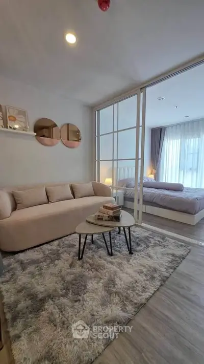 Modern living room with cozy sofa and stylish decor adjacent to a serene bedroom.