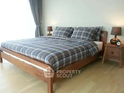 Cozy bedroom with wooden bed frame and plaid bedding, perfect for relaxation.