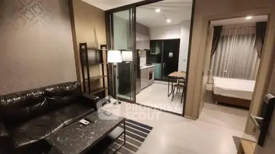 Modern living room with open kitchen and cozy bedroom in stylish apartment.