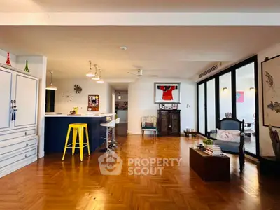 Spacious open-layout living room with stylish decor and wooden flooring.