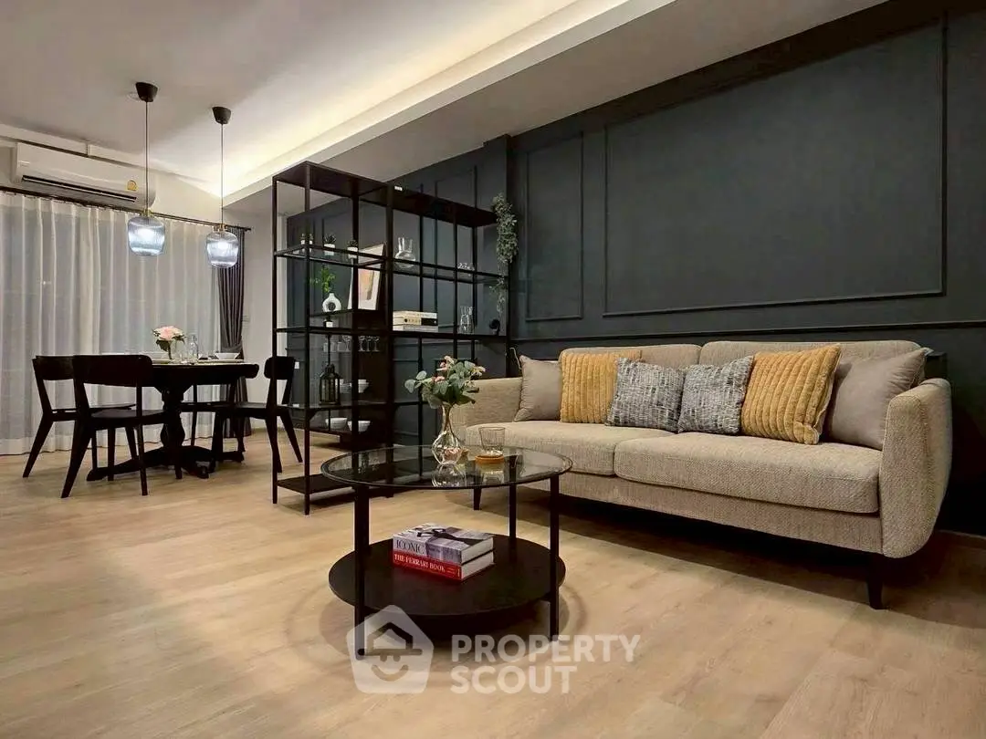 Modern living room with elegant decor and open dining area, featuring stylish furniture and ambient lighting.