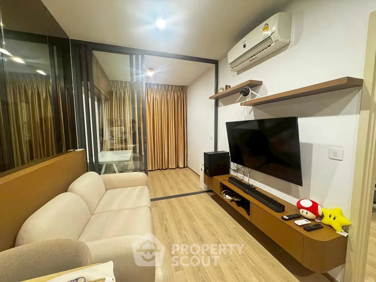Modern living room with sleek design and cozy ambiance, featuring a wall-mounted TV and air conditioning.