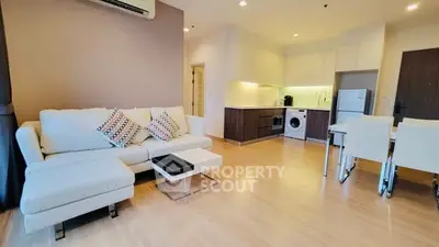 Modern open-plan living room with kitchen, featuring sleek furniture and appliances.
