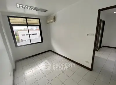 Spacious empty room with large window and air conditioning unit, perfect for customization.