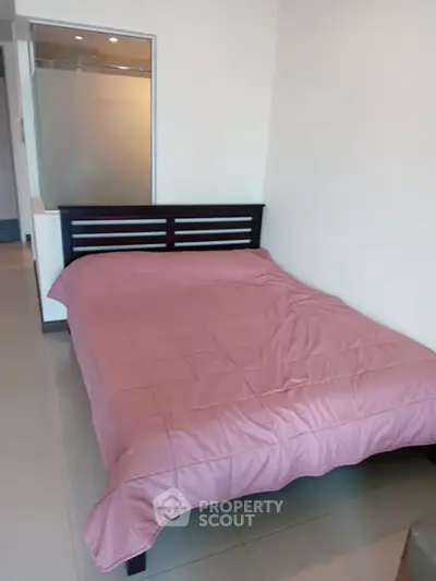 Cozy bedroom with modern bed and pink bedding in a minimalist apartment.