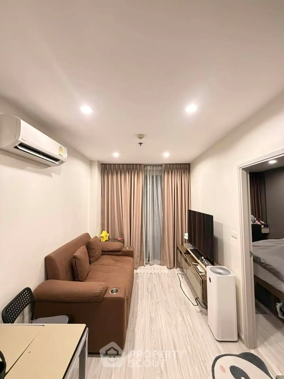 Modern living room with cozy brown sofa, air conditioning, and sleek TV setup in stylish apartment.