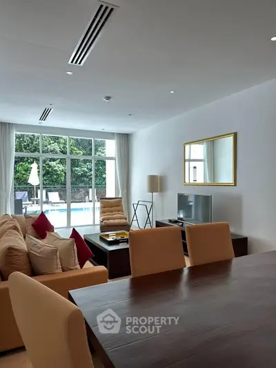 Spacious living room with pool view, modern furniture, and elegant decor in a luxury home.