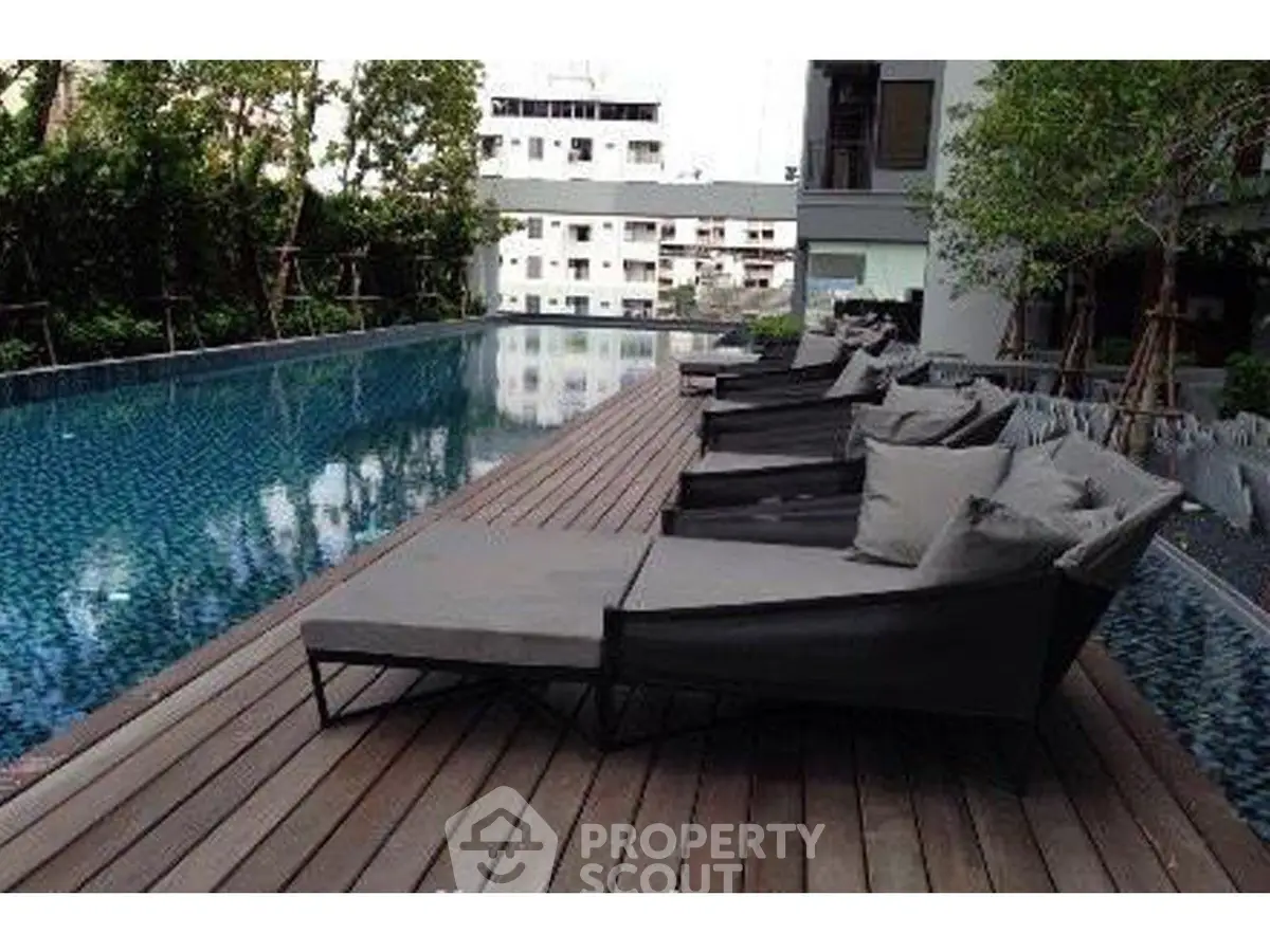 Luxurious poolside area with modern loungers and serene surroundings in a high-end residential complex.