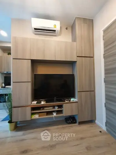 Modern living room with sleek wooden cabinetry and mounted TV, featuring a stylish air conditioning unit.
