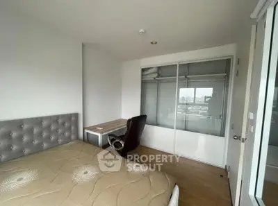 Modern bedroom with city view, featuring a sleek desk and comfortable chair, perfect for urban living.