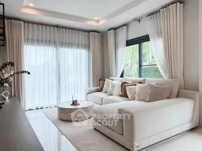 Elegant living room with large windows, plush sofa, and modern decor, offering a bright and inviting atmosphere.