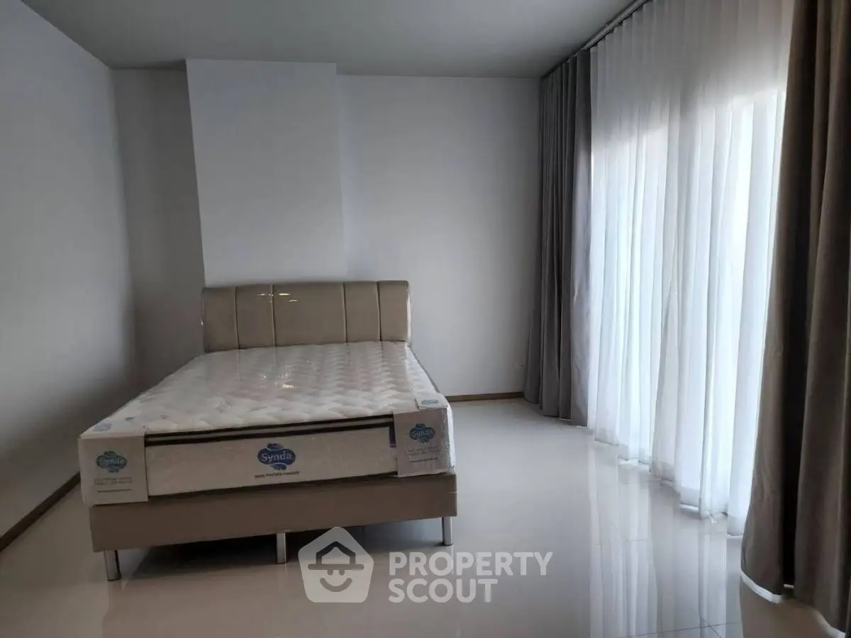 Spacious bedroom with large windows and modern bed frame, perfect for natural light lovers.