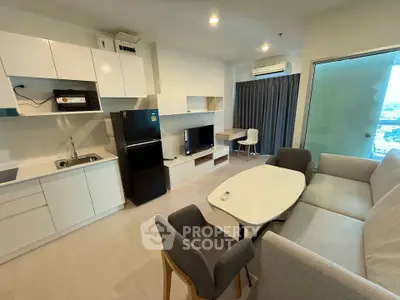 Modern open-layout living room with kitchen, featuring sleek furniture and appliances in a cozy apartment.